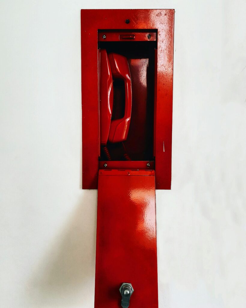 Classic red emergency wall telephone with open panel, showcasing retro design.
